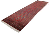 A long vintage Bokhara runner viewed diagonally, showing its fine cherry red pile and gul pattern.