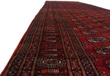 Long perspective view of a vintage Bokhara runner showing the sheen on its plush, cherry red wool pile.