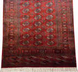 Vintage Bokhara rug runner with its iconic gul medallions repeating across a vibrant cherry red field.