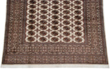 Detailed view of the multi-layered geometric borders and ivory fringe on a fine Bokhara carpet.