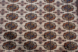Vintage Bokhara carpet detail: geometric floral gul medallions, tight weave, lustrous pile in beige, navy, bronze.