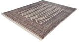 Fine weave detail of beige gul medallions, geometric border, and intact ivory fringe on a Bokhara carpet.