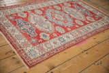 Pakistani Caucasian rug showcasing geometric cherry red, indigo, and ivory medallions.