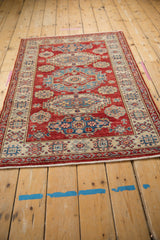 Fringe and intricate geometric motifs on the cherry red and ivory Pakistani Caucasian rug.