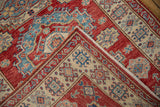 Fringed corner detail of the Pakistani Caucasian rug with red, ivory, and blue geometric hook motifs.