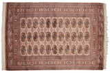 Vintage Bokhara rug with repeating gul medallions on a dusty rose field with navy and brown accents.