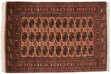 Finely woven Bokhara gul medallions in brown and navy blue on a dusty rose wool rug.