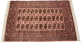 A full view of the plush, silk-like pile of a vintage Pakistani Bokhara rug in dusty rose.
