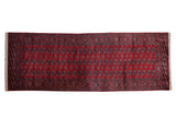A vintage Bokhara rug runner with repeating geometric gul medallions on a rich red field.
