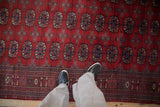 Person's perspective standing on a vintage Bokhara runner with red and navy gul medallions.