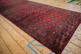 Angled perspective of a vintage Bokhara runner showing its repeating gul motif and lustrous red wool pile.
