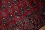 Detailed gul medallions and intricate border on the plush red wool pile of a fine Bokhara rug.