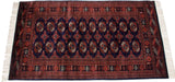 Repeating gul medallions and lustrous wool pile on a navy and rust Bokhara rug.