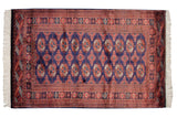 Vintage Bokhara rug with repeating rust and ivory gul medallions on a dark navy blue field.