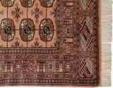 Intact side selvage, fine geometric borders, and cream fringe of a vintage dusty rose Bokhara rug.