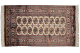 A vintage Pakistani Bokhara rug with a structured design of repeating gul medallions and ivory fringe.