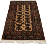 Angled view of a vintage Bokhara rug showing its full length and repeating gul medallions.