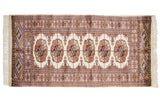 The fine, hand-knotted weave showing detailed gul medallions in navy and bronze.