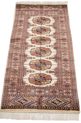 A long perspective view of a vintage Bokhara runner showing the precise alignment of its gul medallions.