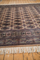 Vintage Bokhara rug's ivory fringe with a small stain, next to geometric borders.