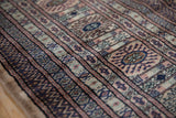 Vintage Bokhara rug with geometric gul medallions in camel, navy, terracotta.