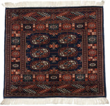 A fine vintage Bokhara rug with rows of rust and ivory elephant footprint guls on a navy blue ground.