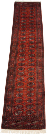 The soft, full wool pile of a vintage Bokhara runner with repeating copper and navy gul medallions.