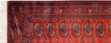 Close-up on the corner of a fine Bokhara rug, highlighting the intact selvage and ivory fringe.