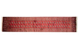 Cherry red Bokhara rug runner with repeating navy blue and ivory geometric floral medallions.