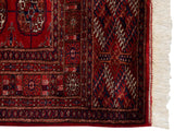 White fringe and cherry red selvage on a plush vintage Bokhara rug.