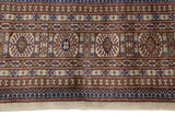 Plush wool pile of a vintage Bokhara carpet showing rows of geometric gul medallions and borders.