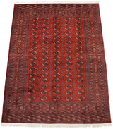 Vintage Bokhara carpet seen from an angle, displaying its lustrous red pile and geometric gul pattern.