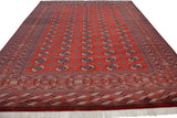 Angled view along the length of a vintage Bokhara carpet showing rows of gul medallions.