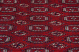 A detailed view of the plush wine-red pile and repeating gul medallions on a vintage Bokhara carpet.