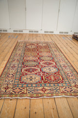 Geometric cherry red Moghan Kazak guls, sapphire blue borders, and white fringe visible.