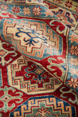 Moghan Kazak design detail featuring intricate red, blue, and ivory geometric patterns.