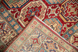 Pakistani Kazak rug's Moghan style border and field patterns in cherry red, sapphire blue, and ivory.