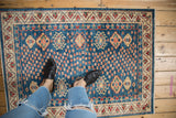 Pakistani Caucasian rug corner, indigo blue field, colorful floral motifs, ivory geometric border.
