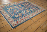 Nuanced indigo field and ivory border with geometric and floral patterns on the Caucasian design rug.
