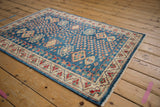 Hand-knotted Pakistani Caucasian rug corner with indigo field, ivory geometric border, and selvage.