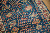 Pakistani Caucasian rug's low pile indigo field with red floral motifs and ivory border.