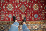 Vibrant cherry red Pakistani Caucasian rug showcasing geometric diamond medallions and a crab style vine border.