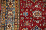 Cherry red field of the Pakistani Caucasian design rug with its vibrant geometric main border.