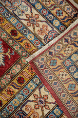 Hand-knotted Pakistani Caucasian rug's folded edge, with cherry red border and geometric vine motifs.