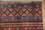 Fringed upper edge of a Pakistani Khorjin rug, displaying gem-tone horizontal banded patterns.