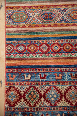 Pakistani Khorjin rug with horizontal bands, diamond medallions, and stylized bird motifs in gem tones.