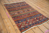 Detail of a hand-knotted Khorjin rug showing gem-toned horizontal stripes and geometric diamond medallions.
