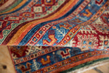 Banded Khorjin design rug detail, featuring gem-like sapphire blue, cherry red, and tangerine pile.