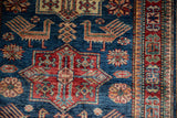 Close-up of sapphire blue Caucasian rug field with finned birds and bursting floral motifs.