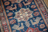 Stylized apricot bird and red floral patterns on a rich blue rug background.